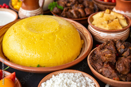 Homemade Romanian Food with polenta, meat, cheese and vegetables. Delicious corn porridge in clay dishes. Mamaliga or polenta, a traditional dish in Moldova, Hungary and Ukrainian cuisine. 