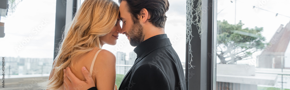 Side view of bearded man hugging blonde girlfriend in restaurant, banner. Side view of bearded man hugging blonde girlfriend in restaurant, banner.