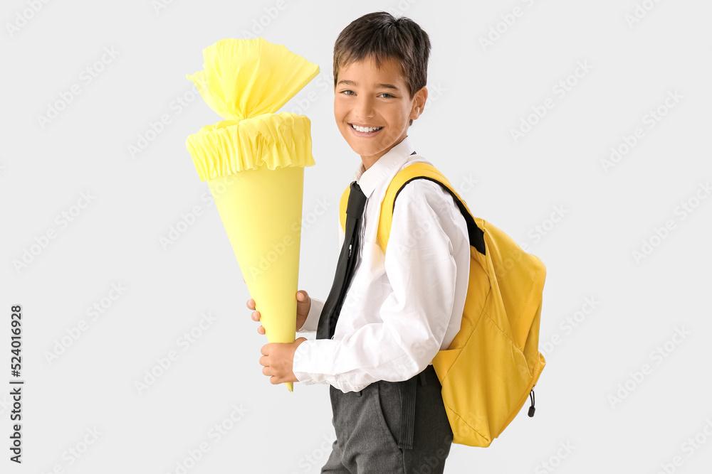 Little boy with yellow school cone and backpack on light background Little boy with yellow school cone and backpack on light background
