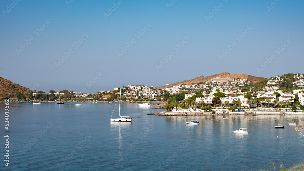 View of Bodrum Beach, Aegean sea, traditional white houses, flowers, marina, sailing boats, yachts in Bodrum town Turkey. Front view