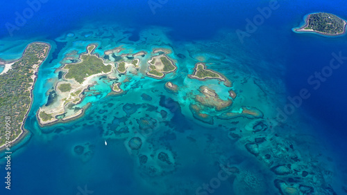 Aerial drone photo of tropical exotic paradise island bay with deep turquoise sea forming a blue lagoon visited by luxury yachts and sail boats