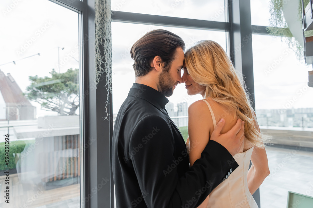 Side view of elegant man hugging blonde girlfriend in restaurant. Side view of elegant man hugging blonde girlfriend in restaurant.