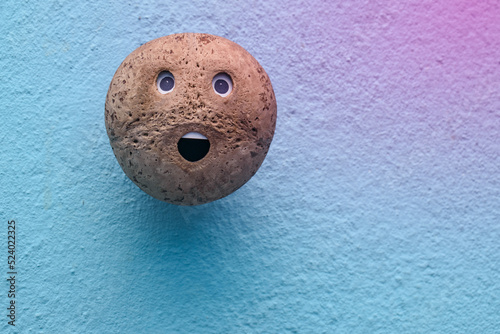Coconut shell smiley face on wall background. handmade emoji emoticon head. Mental health care concept 