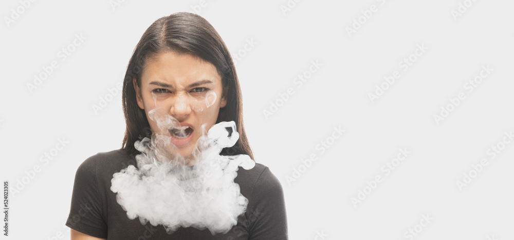 Angry young girl with dark hair releases smoke from the mouth isolated over white background. Concept of mental health, art, human emotions Angry young girl with dark hair releases smoke from the mouth isolated over white background. Concept of mental health, art, human emotions