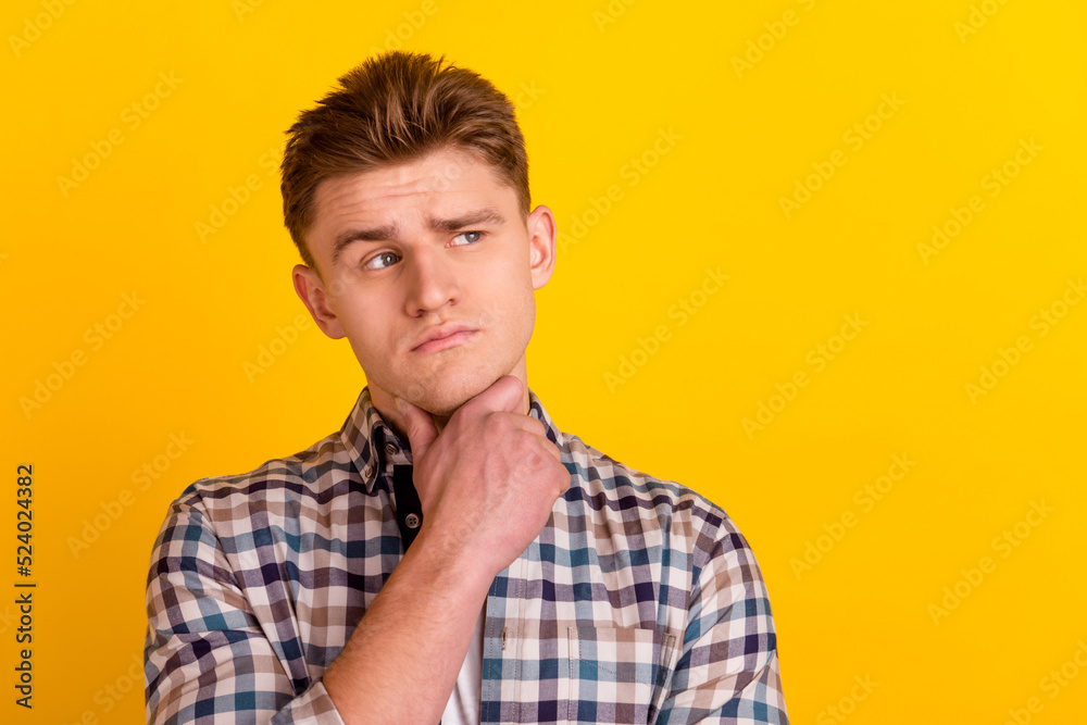 Photo of young man hand touch chin thoughtful ponder look empty space isolated over yellow color background Photo of young man hand touch chin thoughtful ponder look empty space isolated over yellow color background