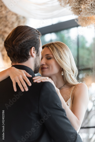 Blonde woman hugging boyfriend in suit in restaurant.
