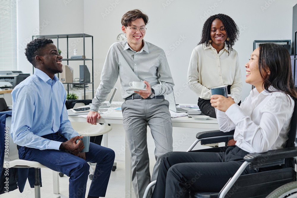 Group of young colleagues laughing and talking during coffee break at office Group of young colleagues laughing and talking during coffee break at office
