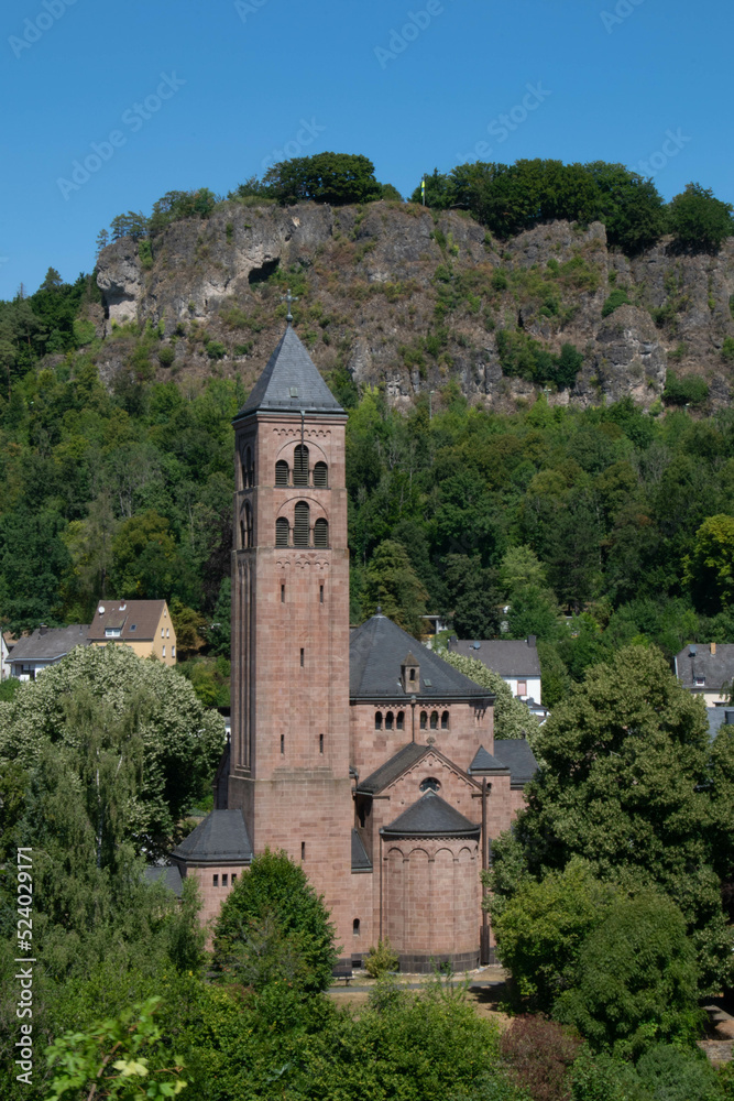 Church in the village of Gerolstein in the German Eifel with the rocks of the Gerolsteiner Dolomites in the background and the view point Munterley