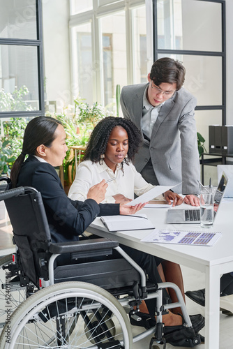 Asian businesswoman with disability working with her colleagues at meeting at office