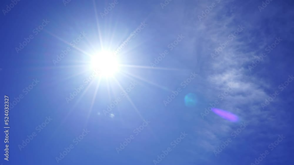 Nature view of direct bright noon sun on blue sky with clouds Sun shining on summer horizon in vibrant sunlight Sunbeam and sun ray flares with white cumulus clouds in midday sunshine day