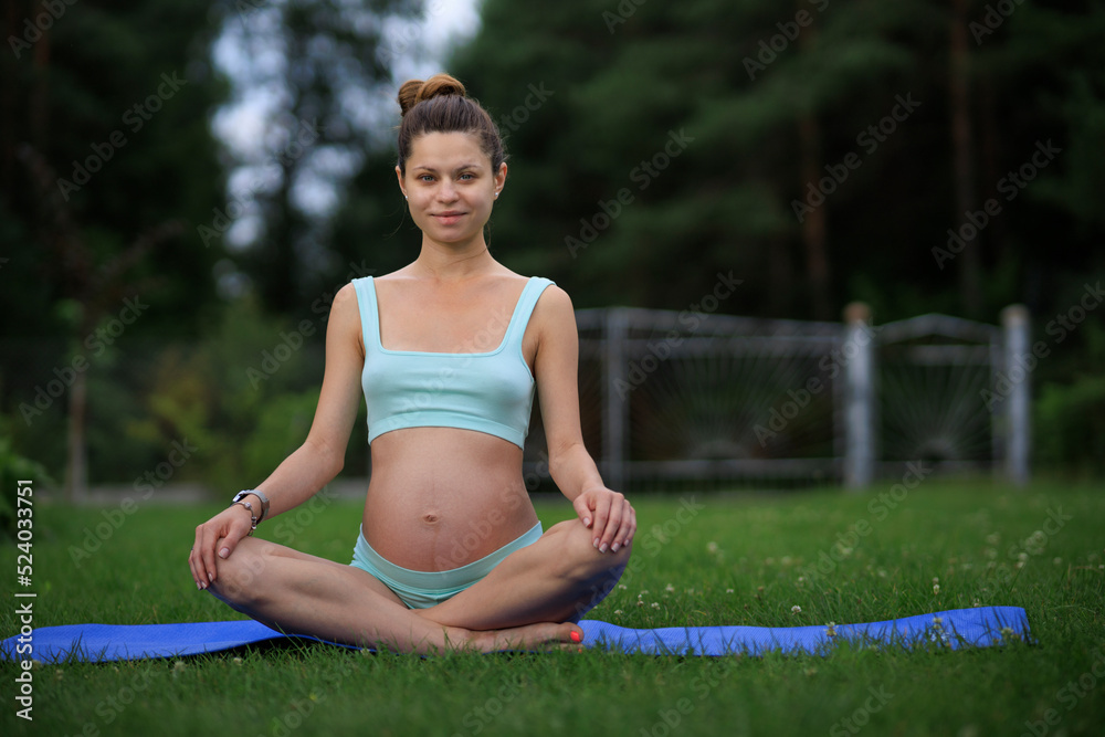 Health concept. Young beautiful pregnant woman does yoga exercise on the grass in nature. Health concept. Young beautiful pregnant woman does yoga exercise on the grass in nature.