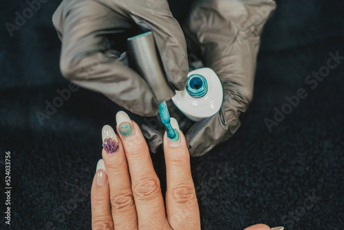 a professional painting a woman's nails in her beauty center. Close up of the hands