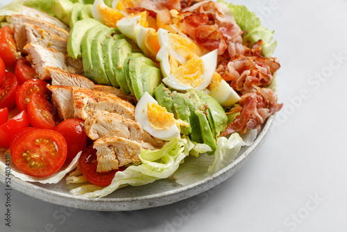 Cobb salad with bacon, avocado, tomato, grilled chicken, eggs isolated on  white background. American salad. Healthy food.