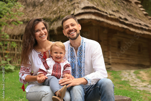 Happy family in Ukrainian national clothes sitting on bench outdoors © New Africa