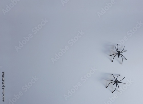 Two small artificial spiders with long legs on a gray background. Creative halloween concept backdrop. halloween craft.