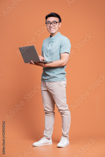 Full length image of young Asian man standing on backgound