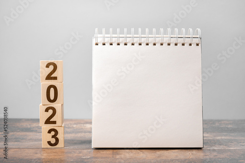 Mockup 2023 calendar. Text 2023 on wooden cubes. space for your text on notepad, mockup calendar. New Year. startup concept. Year 2023 and notepad