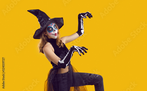 Foto Portrait of funny child in Halloween disguise dancing isolated on yellow color background