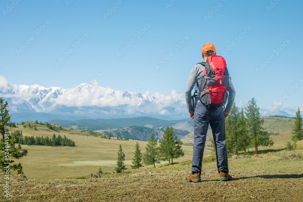 Man traveling with backpack hiking in mountains. Man hiker looks on the beautiful landscape and  thinks. Travel Lifestyle wanderlust adventure concept.