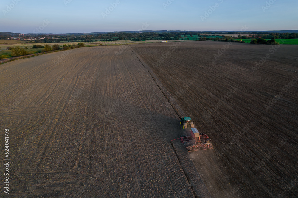 Fototapeta premium The tractor mills the field. Modern machinery in the farmer's field. Top view.