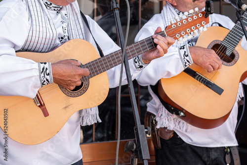 Close-up of a duo of male musicians playing their guitars and singing outdoors.