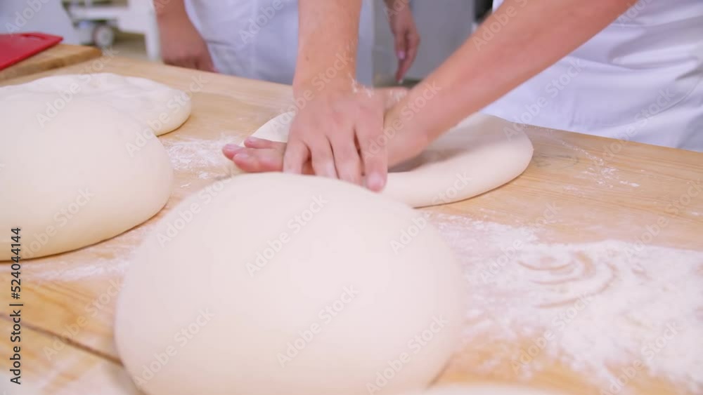 Close-up of dough kneaded by baker on a wooden board sprinkled with flour Close-up of dough kneaded by baker on a wooden board sprinkled with flour