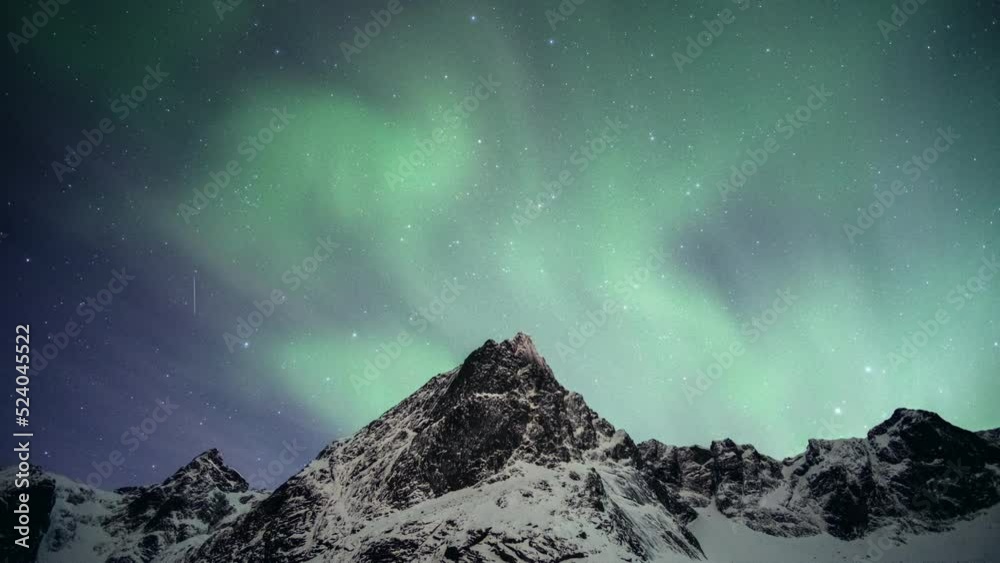 Beautiful green Aurora Borealis, Northern Lights glowing over snowy mountain on winter in Nordland at Lofoten Islands, Norway