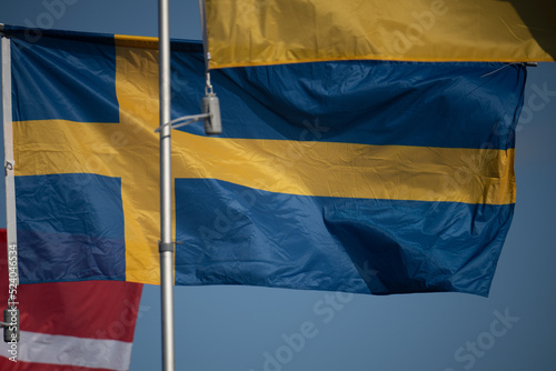 Flag of Sweden on flagpole waving in the wind on a beautiful sunny day with blue sky photo