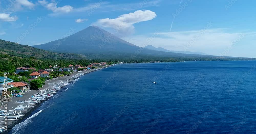 Coast of island with black sand beach and volcano erupting in background Coast of island with black sand beach and volcano erupting in background