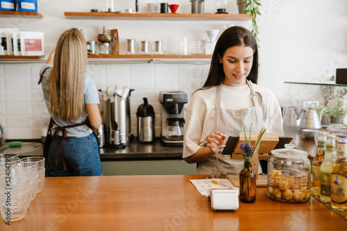 White two barista women smiling while working together in cafe