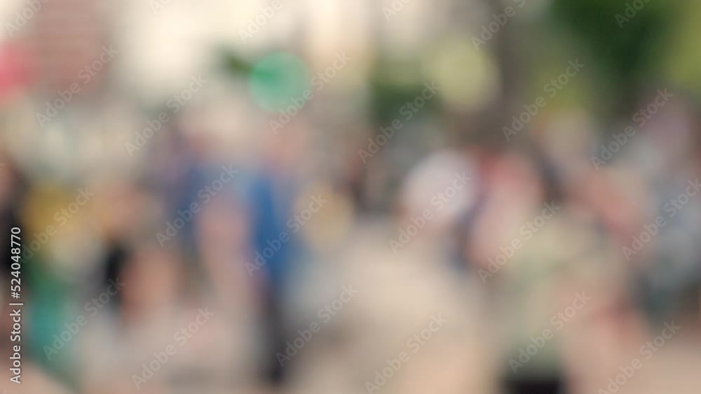 Lens blur, out of focus. a crowd of pedestrians are walking along the street Lens blur, out of focus. a crowd of pedestrians are walking along the street
