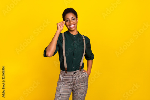 Portrait of attractive cheerful intellectual woman touching specs posing isolated over bright yellow color background