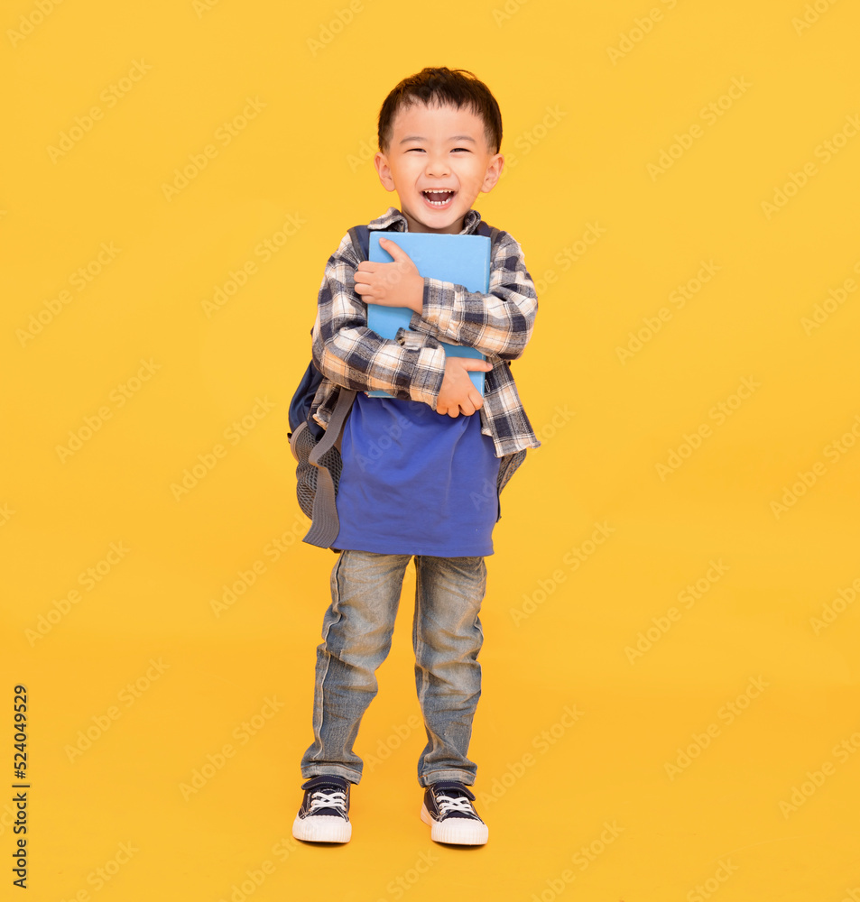 happy asian kid holding or hugging  big book over yellow background