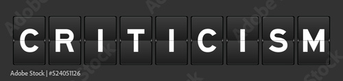 Black color analog flip board with word criticism on gray background