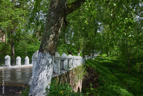 An old bridge with white pillars among green trees.