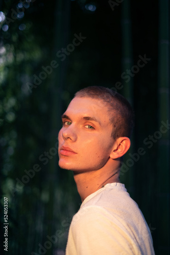 Close up portrait of young handsome caucasian male model looking boldly at camera in bamboo park