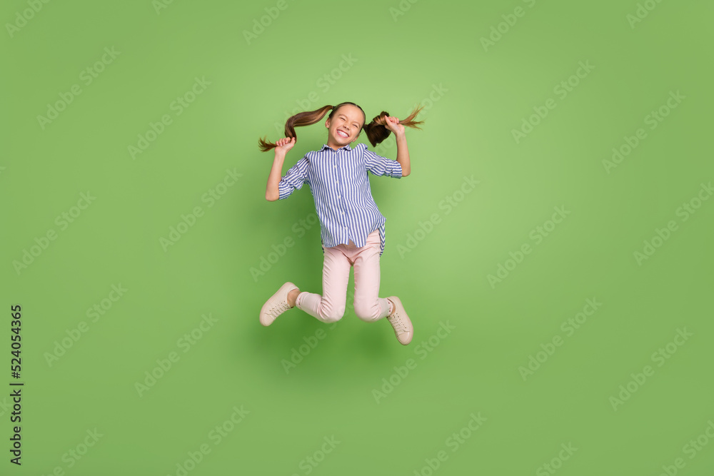 Photo of excited student year kid jump high hold hairstyle tails wear striped shirt isolated bright color background Photo of excited student year kid jump high hold hairstyle tails wear striped shirt isolated bright color background