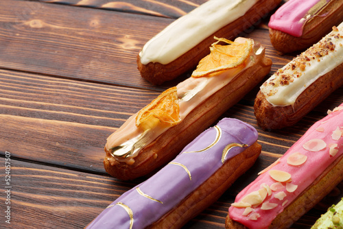 Bild auf Leinwand Assortment of sweet and colorful eclairs on wooden background