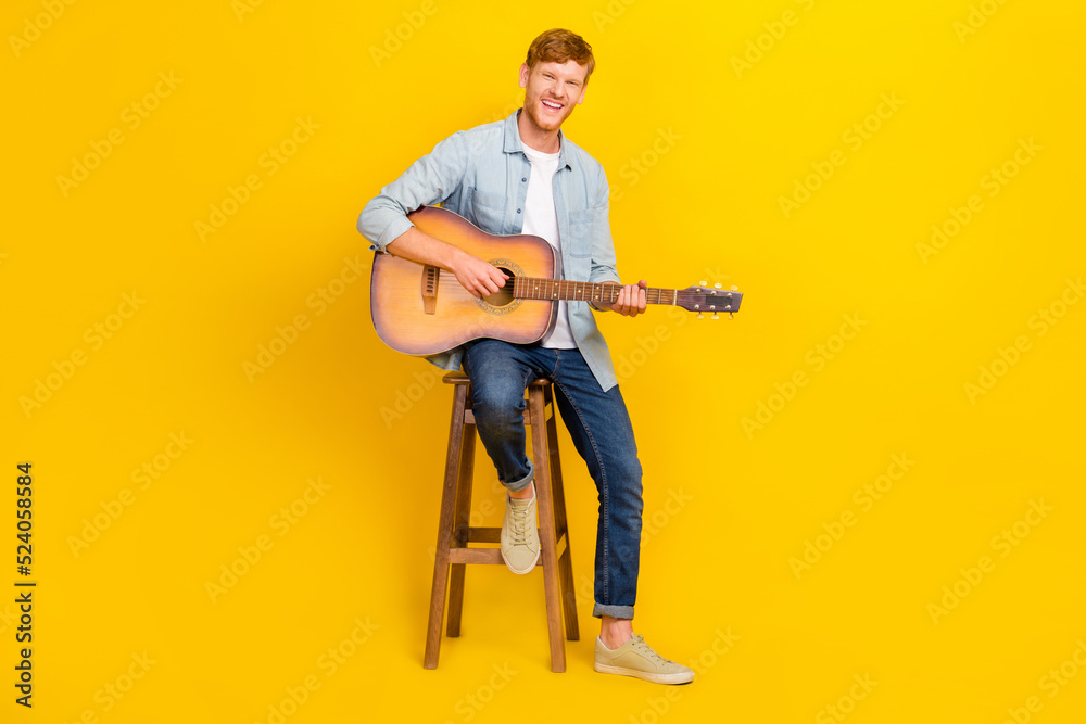 Full length photo of young handsome man boyfriend sing song guitar music for girl isolated on yellow color background Full length photo of young handsome man boyfriend sing song guitar music for girl isolated on yellow color background