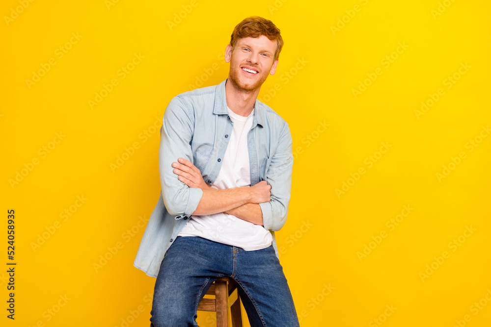 Fototapeta premium Photo of attractive sweet guy dressed denim shirt hands folded sitting chair empty space isolated yellow color background