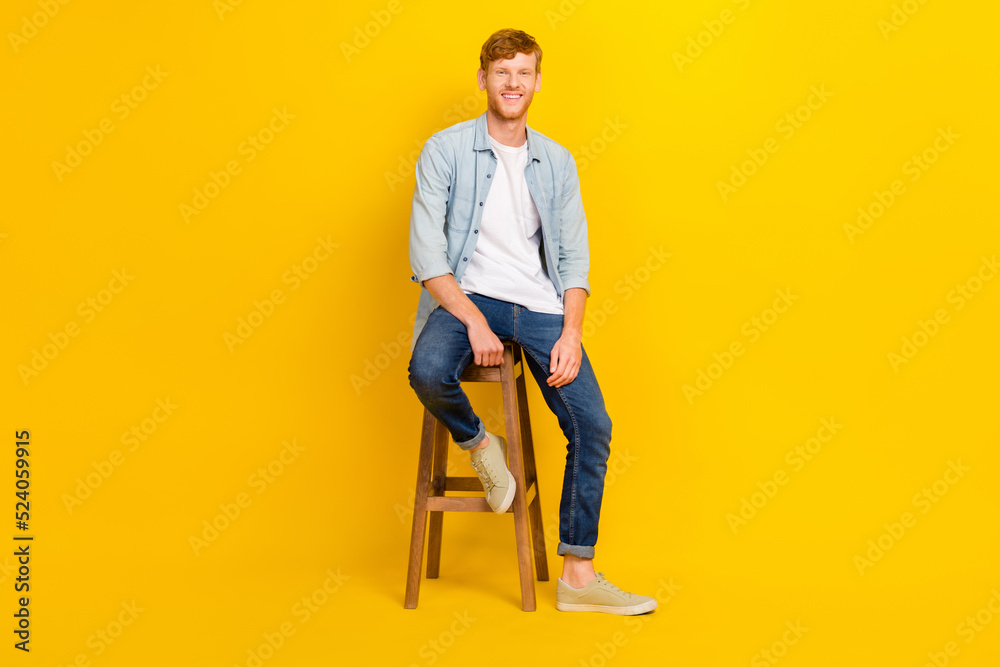 Full size photo of young creative handsome guy wear casual clothes sitting chair waiting end lesson isolated on yellow color background Full size photo of young creative handsome guy wear casual clothes sitting chair waiting end lesson isolated on yellow color background