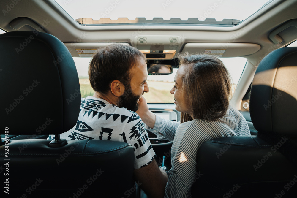 Happy middle-aged couple enjoying road trip together, cheerful caucasian man and woman sitting inside the SUV car while on vacation
