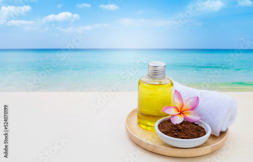 Coffee powder with cleansing gel with white towel in wooden tray over blurred beach background, spa concept background