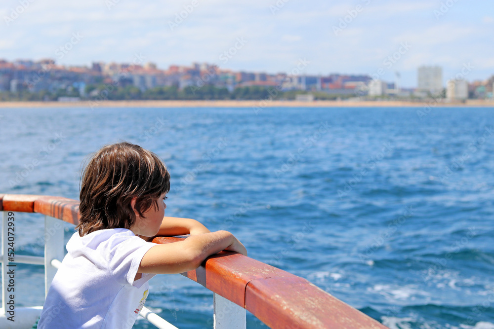 Fototapeta premium A little boy leaning out of the stern of a ship