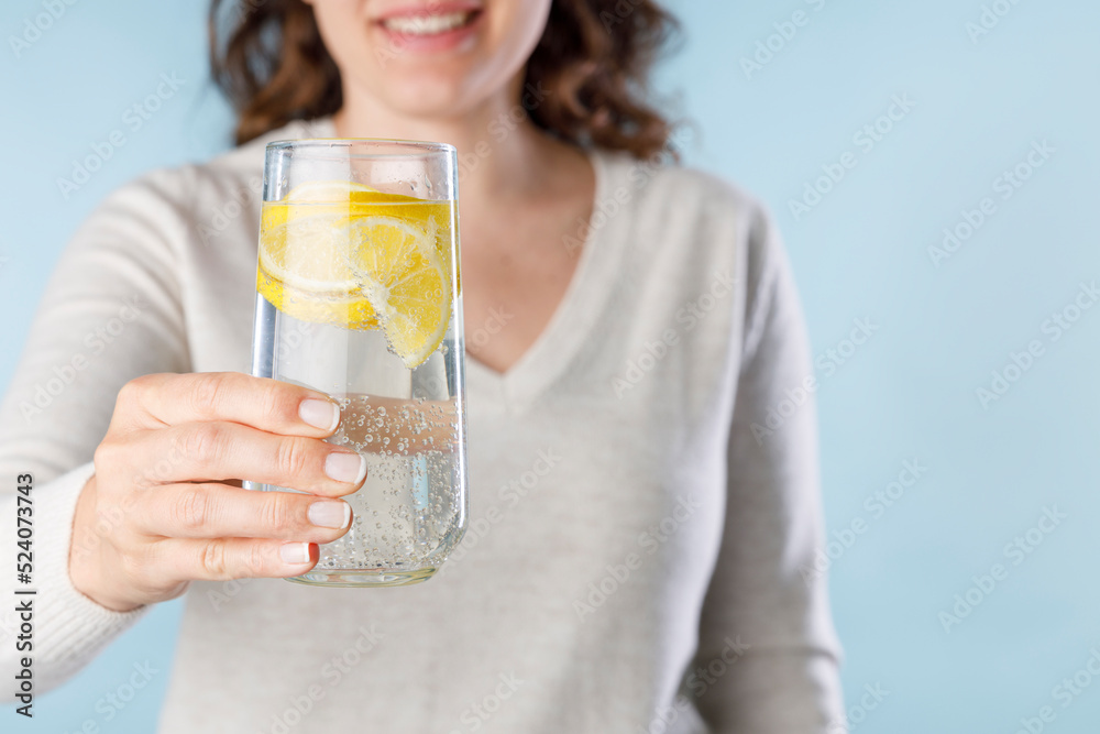 Young woman holding a glass of mineral water with lemon. Healthy lifestyle, diet and fitness. Young woman holding a glass of mineral water with lemon. Healthy lifestyle, diet and fitness.