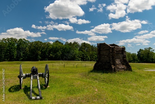 Gatling gun set in an open field with a wooden little fort next to it photo