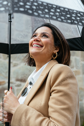 Happy female laughing under umbrella