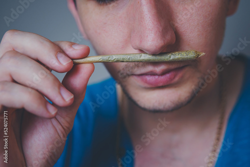Close-up of adult man lights up with matches and smoking medical marijuana joint. Concept of herbal and alternative medicine