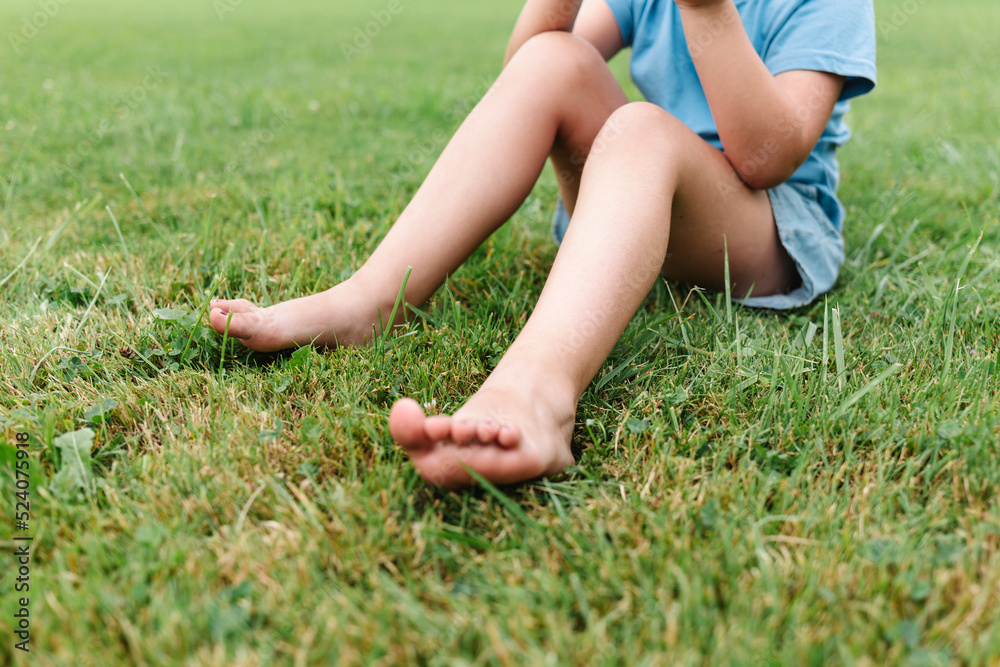 Crop child sitting on grass Crop child sitting on grass