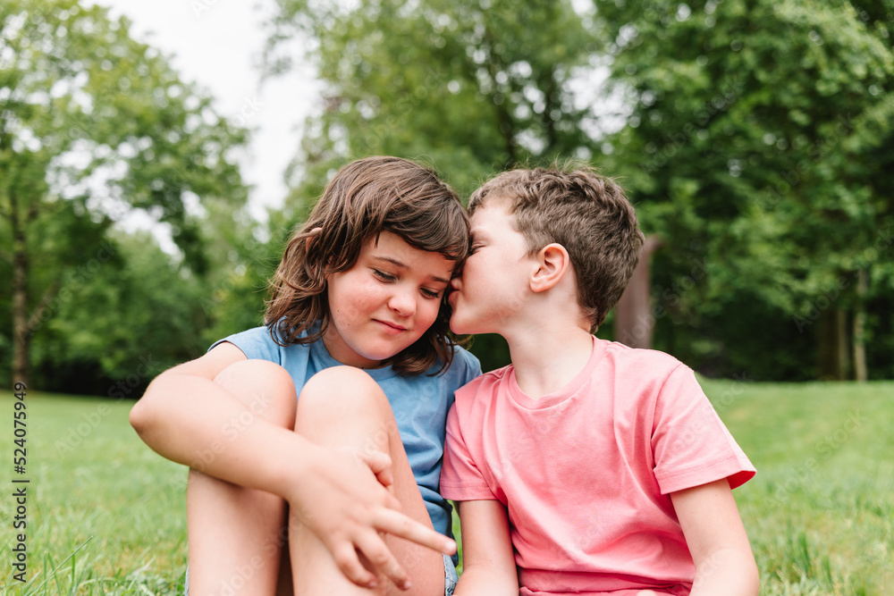 Brother telling secret to sister in park Brother telling secret to sister in park